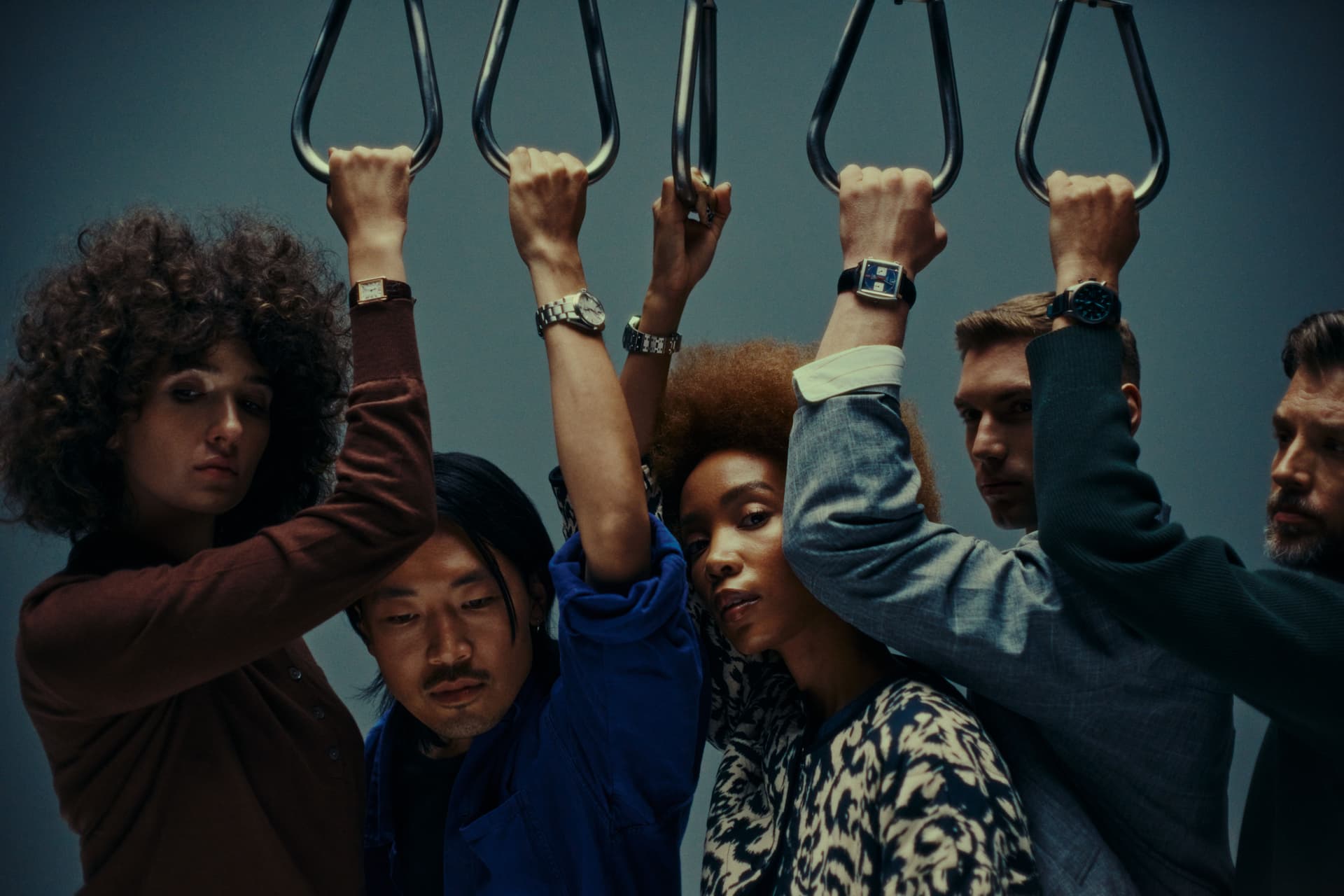 group of people on subway holding handles in a cramped line with blue background
